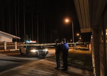 Gece vakti sokakta polis ekipleri ve güvenlik şeridi önünde duran şüpheli