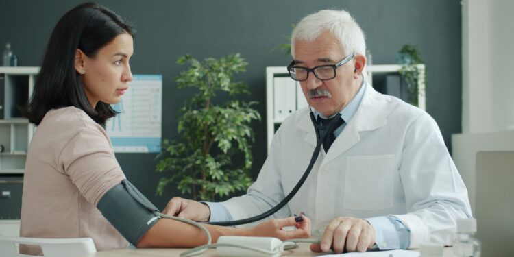 Bir aile sağlığı merkezinde doktor hastanın tansiyonunu ölçüyor.