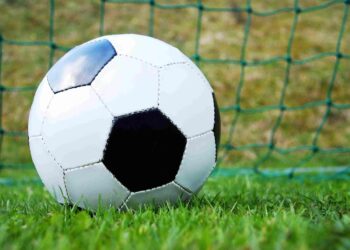 Çim sahada kaleye yaslanmış bir futbol topu yakın plan çekim.