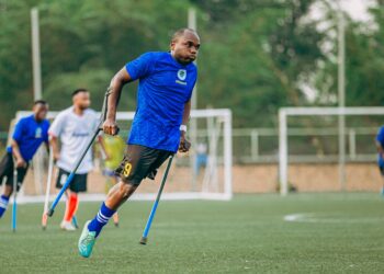 Mavi formalı ampute futbolcu sahada koltuk değnekleriyle koşuyor.