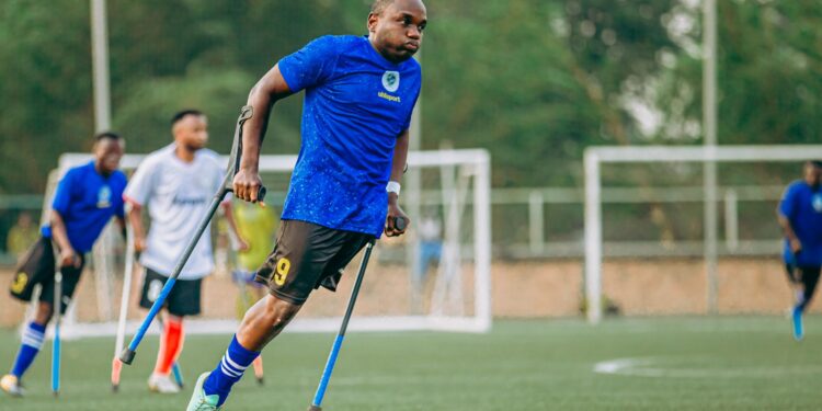 Mavi formalı ampute futbolcu sahada koltuk değnekleriyle koşuyor.