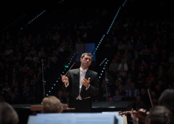 Klasik müzik konserinde orkestrayı yöneten kulaklıklı erkek şef.