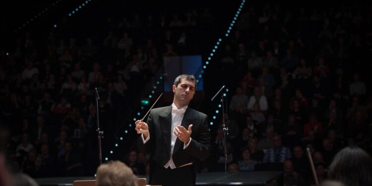 Klasik müzik konserinde orkestrayı yöneten kulaklıklı erkek şef.