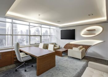 Şehir manzaralı geniş pencereleri olan modern bir ofis odası.