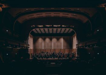 Devasa tarihi konser salonunun sahnesinde performans sergileyen geniş senfoni orkestrası.