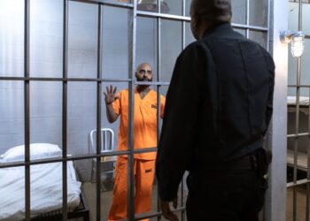 Hapishane hücresinde parmaklıklar ardındaki bir mahkum ile polis memurunun konuşma anı.