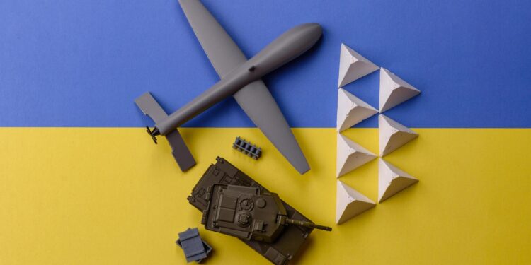 Mavi sarı zemin üzerinde dron, tank ve askeri engellerin yer aldığı maketler.