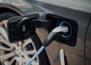 Gri renkli elektrikli bir otomobilin şarj istasyonundan kablo ile şarj edilişi.