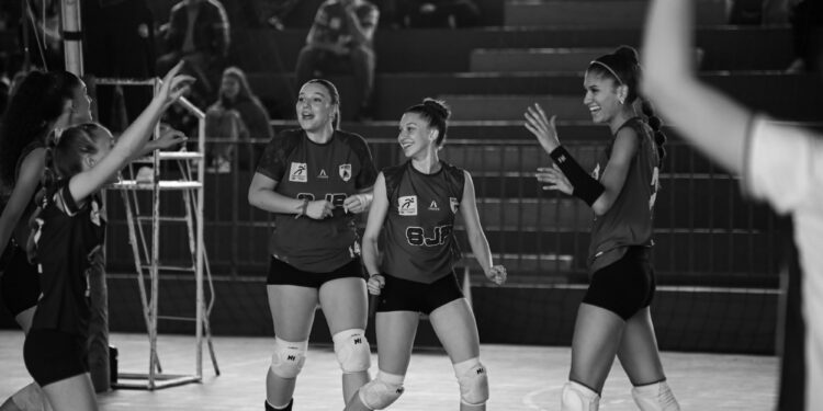 Siyah-beyaz karede voleybol oynarken sevinç yaşayan neşeli kadın sporcular yer alıyor.