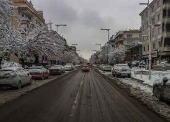 Karlı ve buzlu bir yolda hareket eden otomobillerin geniş açıdan görünümü.