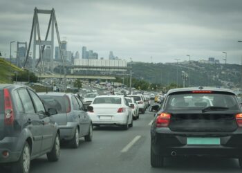 İstanbul köprüsü üzerinde yoğun trafikte sıkışmış araçlar ve arka planda şehir silüeti.