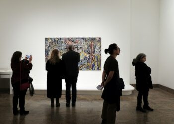 Sanat galerisinde soyut bir tabloyu inceleyen sanatseverler.