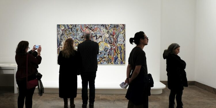 Sanat galerisinde soyut bir tabloyu inceleyen sanatseverler.