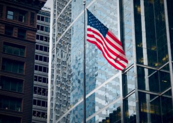 Şehir merkezindeki yüksek binalar arasında dalgalanan Amerika Birleşik Devletleri bayrağı.