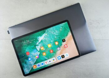 Gri dizüstü bilgisayarın üzerine yerleştirilmiş renkli ekranlı modern bir tablet.