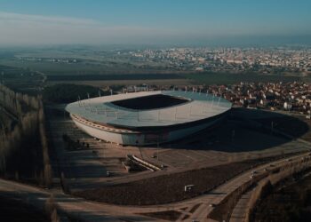 Yeşil sahada topa vuran futbolcu çocuğun genel görünümü