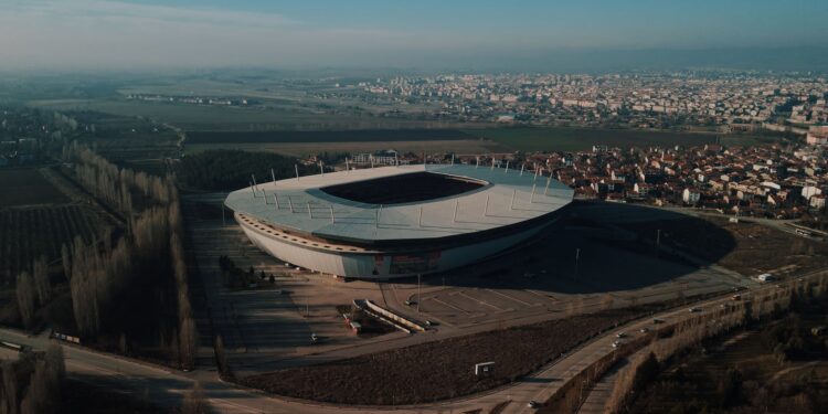 Yeşil sahada topa vuran futbolcu çocuğun genel görünümü