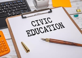 Ahşap masanın üzerinde 'Civic Education' yazan bir belge ve kalem.