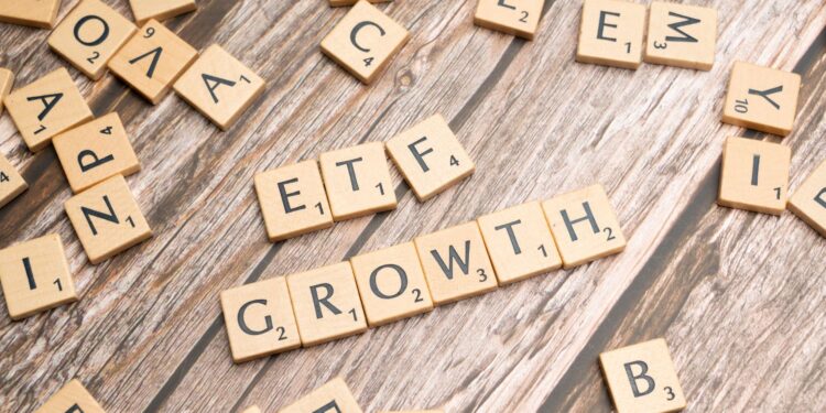 Ahşap masa üzerinde ETF ve GROWTH yazan Scrabble harfleri ve etraftaki harfler.