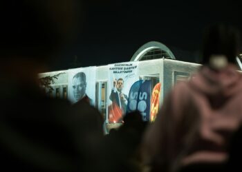 Gece vakti parti binası önünde toplanan kalabalık ve pankartlar