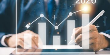 Takım elbiseli bir kişi dijital grafik üzerine dijital kalemle yazıyor.